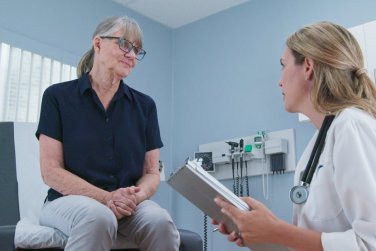 doctor taking medical history from older patient in exam room.