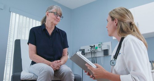 doctor taking medical history from older patient in exam room.
