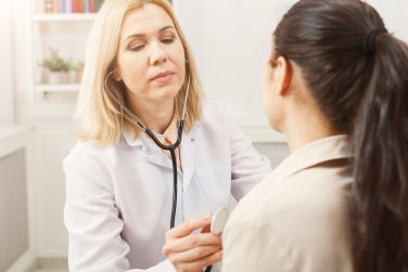 doctor examines patient with a stethoscope.