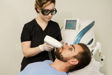 provider holding treatment applicator to patient's face.