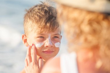 woman applying sunscreen to boy's face.