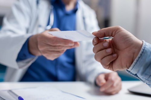 patient hands doctor a sheet of paper.