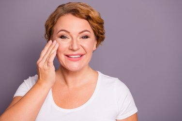 cheerful woman touches her cheek.