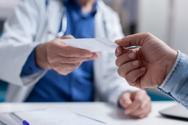 patient hands doctor a sheet of paper.