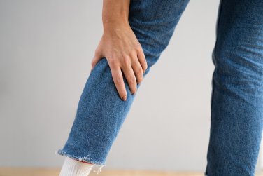 person reaching backward holding shin.