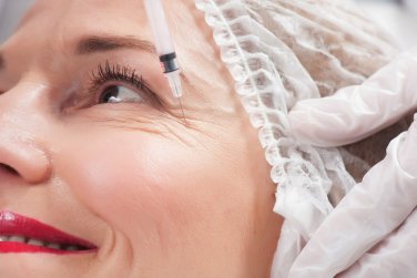 provider holds needle near woman's eye wrinkles.