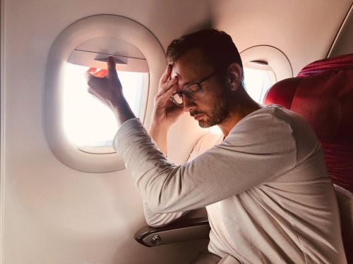 靠窗的航空乘客看起来生病或疲惫。