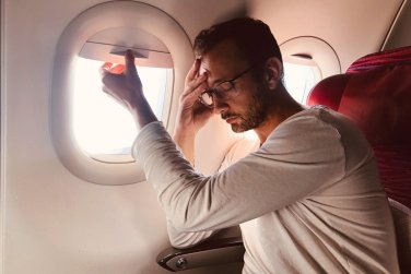 airline passenger by window looks sick or tired.
